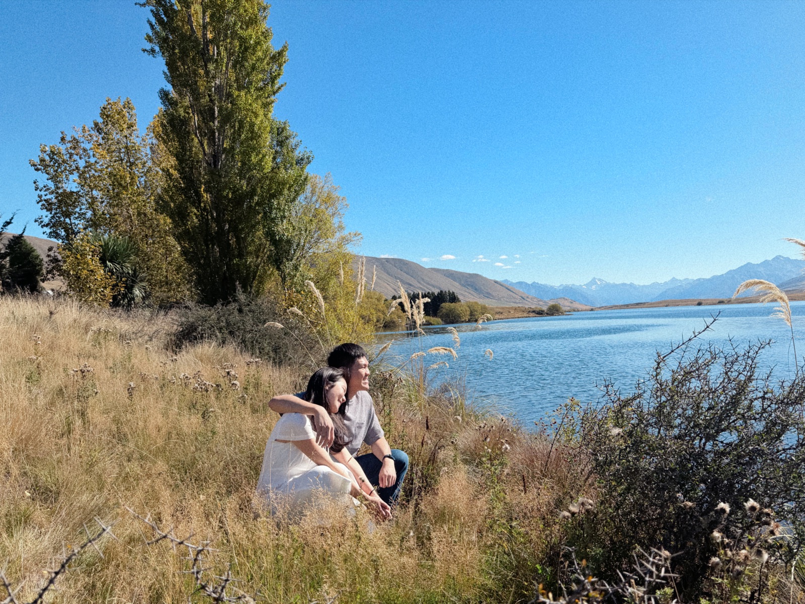 Gabriel and Estella sitting by a New Zealand lake